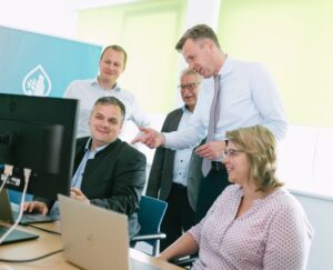 Fünf Personen sind schauen um einen PC versammelt auf dessen Bildschirm.