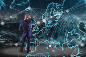 Ein Mann steht überlegend vor einer Technologie-Netzwerkweltkarte, die auf einer futuristischen Schnittstelle angezeigt wird.