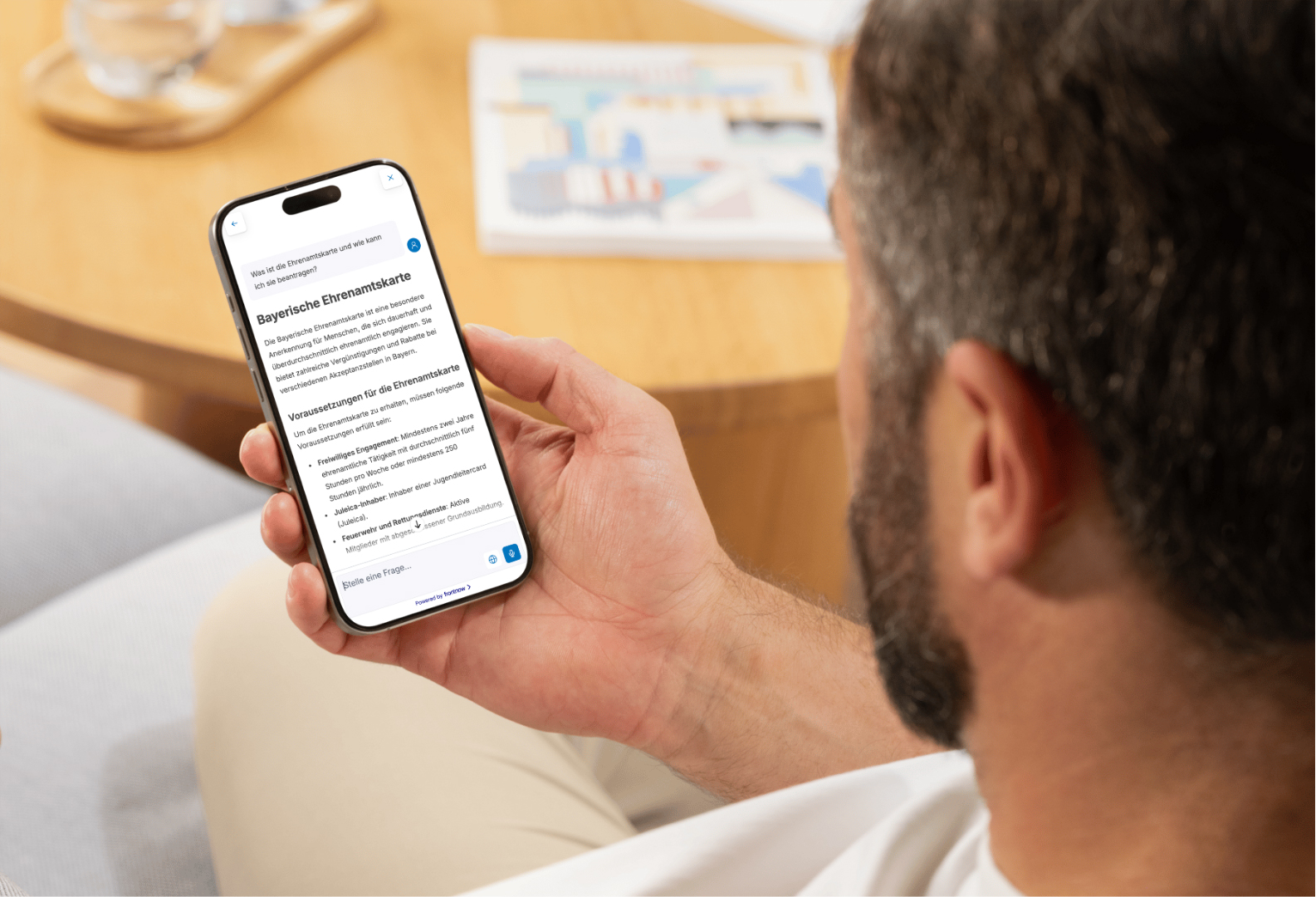 Ein Mann schaut in ein Smartphone, auf dem Informationen aus der Verwaltung zu sehen sind.