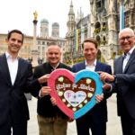 Vier Männer halten ein Lebkuchenherz in die Kamera