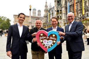 Vier Männer halten ein Lebkuchenherz in die Kamera