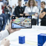 Eine Person präsentiert anderen Personen über ein Tablet eine Stadtkarte.