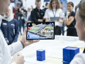 Eine Person präsentiert anderen Personen über ein Tablet eine Stadtkarte.