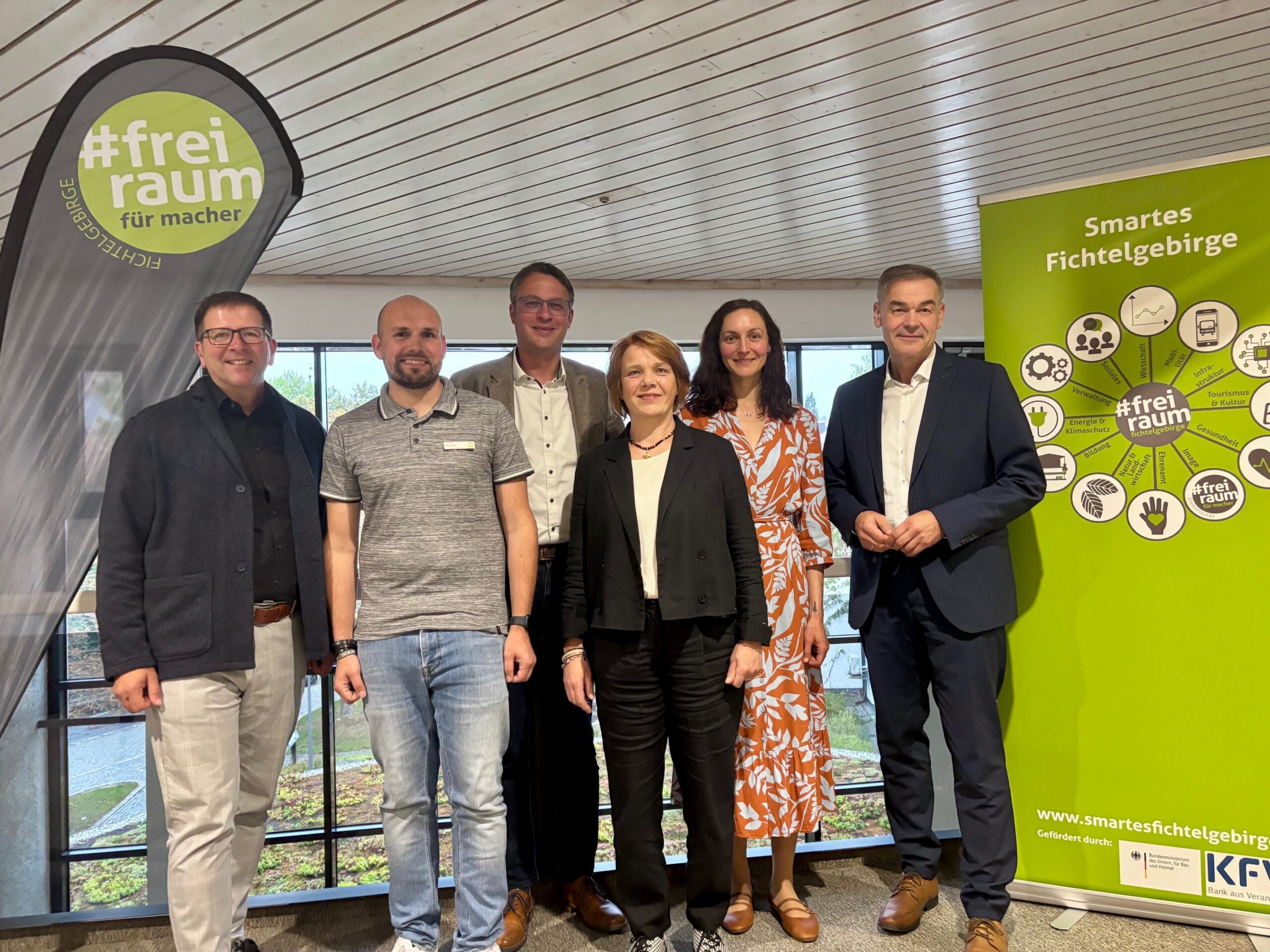 Gruppenfoto mit sechs Personen in einem nüchternen Innenraum, im Hintergrund Banner "Smartes Fichtelgebirge".