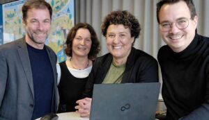 Vier Mitarbeitende der Stadt Potsdam versammeln sich um einen Laptop