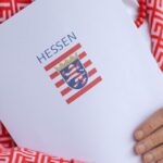 Ein Dokumentenordner mit dem hessischen Wappen in den Armen einer Frau.