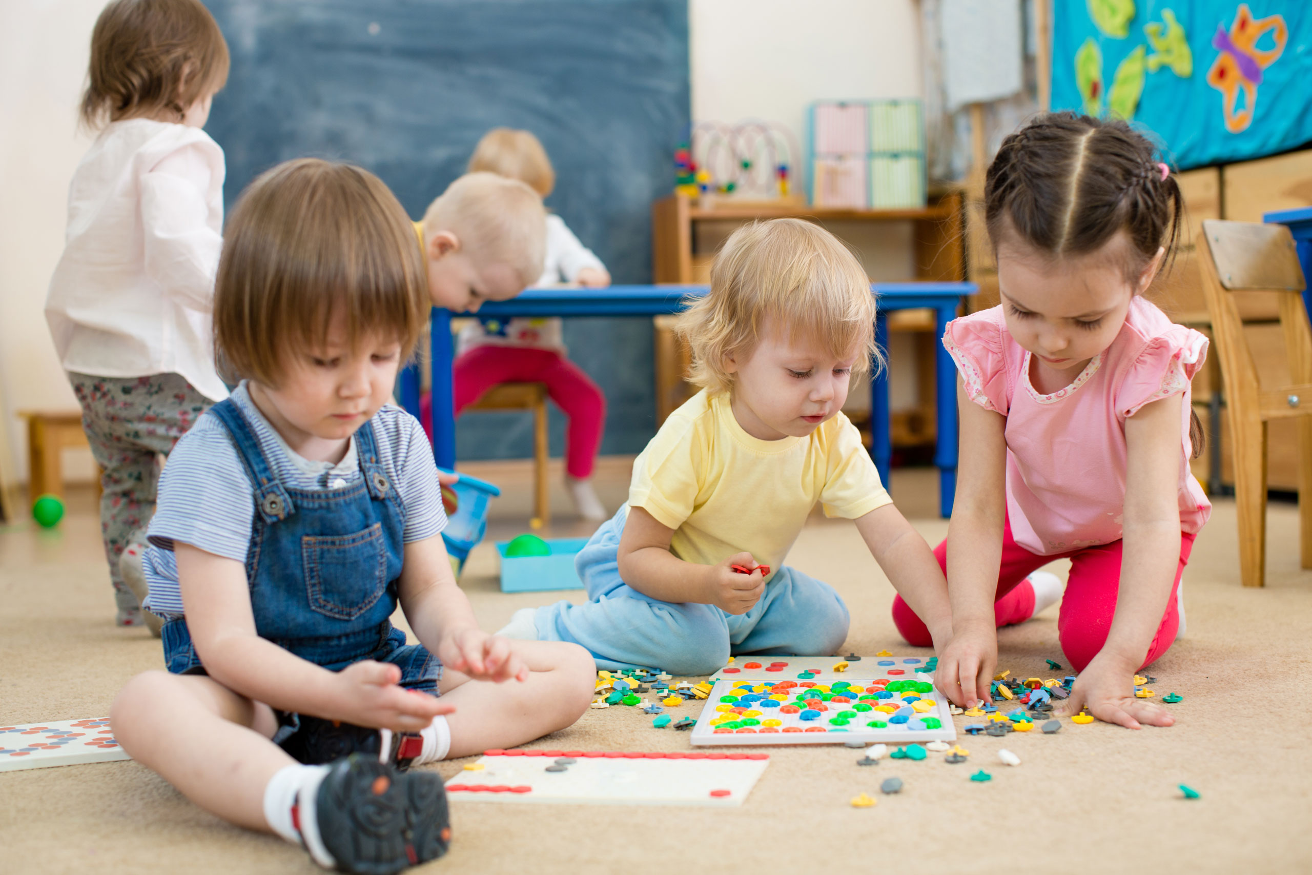 Drei Kleinkinder spielen mit Bauklötzen.