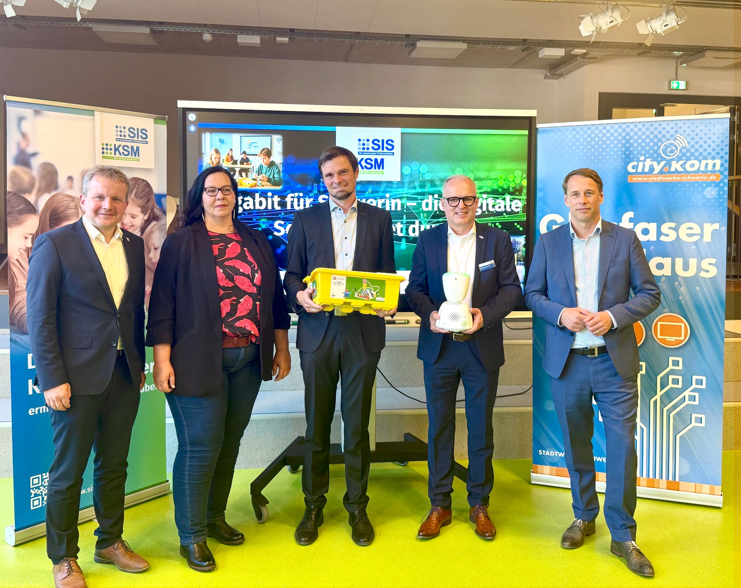 Fünf Personen stehen nebeneinander, eine davon hält ein LEGO Education SPIKE Set in den Händen.