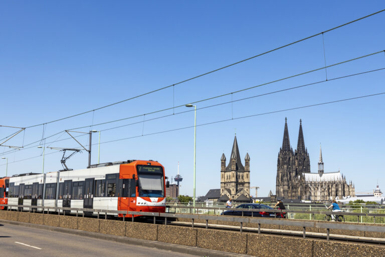 Eine Stadtbahn der Kölner Verkehrsbetriebe fährt am Stadtzentrum mit dem Kölner Dom vorbei.