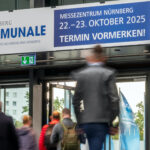 Über dem Ausgang einer Messehalle hängt ein Banner, das auf die Daten der Kommunale 2025 hinweist.