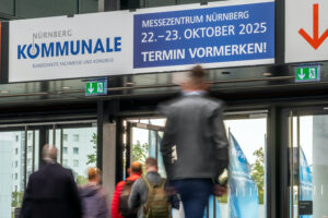 Über dem Ausgang einer Messehalle hängt ein Banner, das auf die Daten der Kommunale 2025 hinweist.