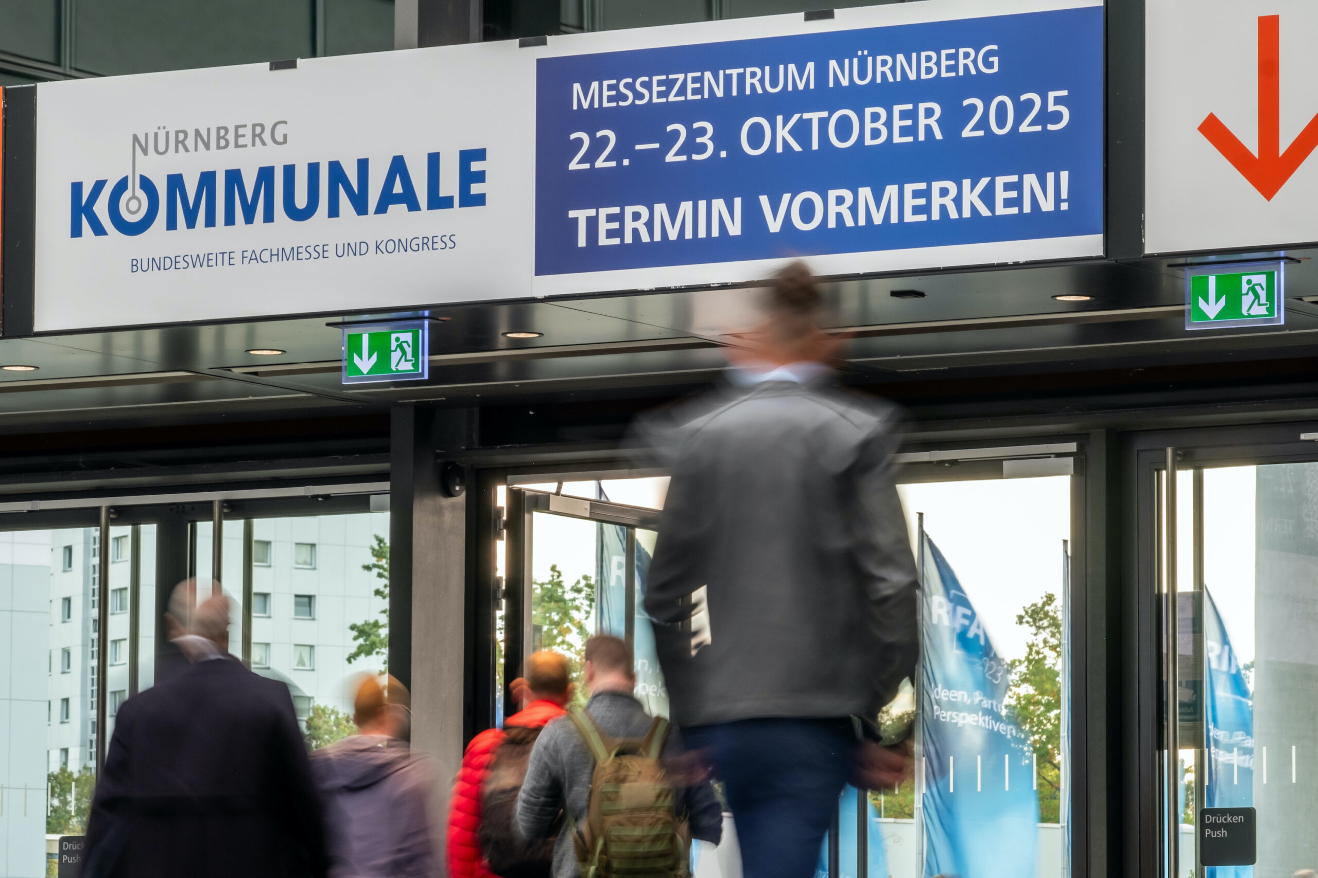 Über dem Ausgang einer Messehalle hängt ein Banner, das auf die Daten der Kommunale 2025 hinweist.