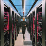 Eine Frau steht inmitten eines Rechenzentrums.