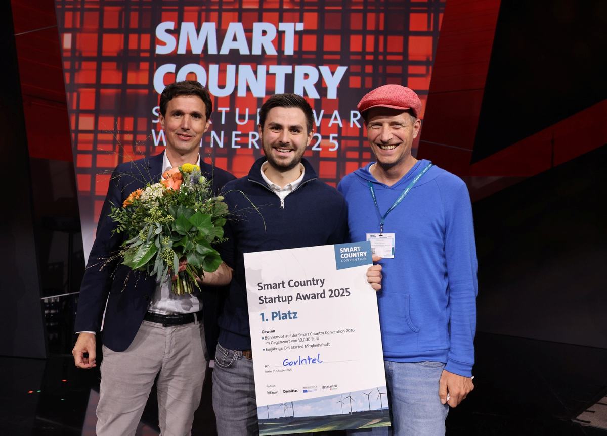 GovIntel gewinnt Startup Award. Drei Männer mit Blumenstrauß und Urkunde.