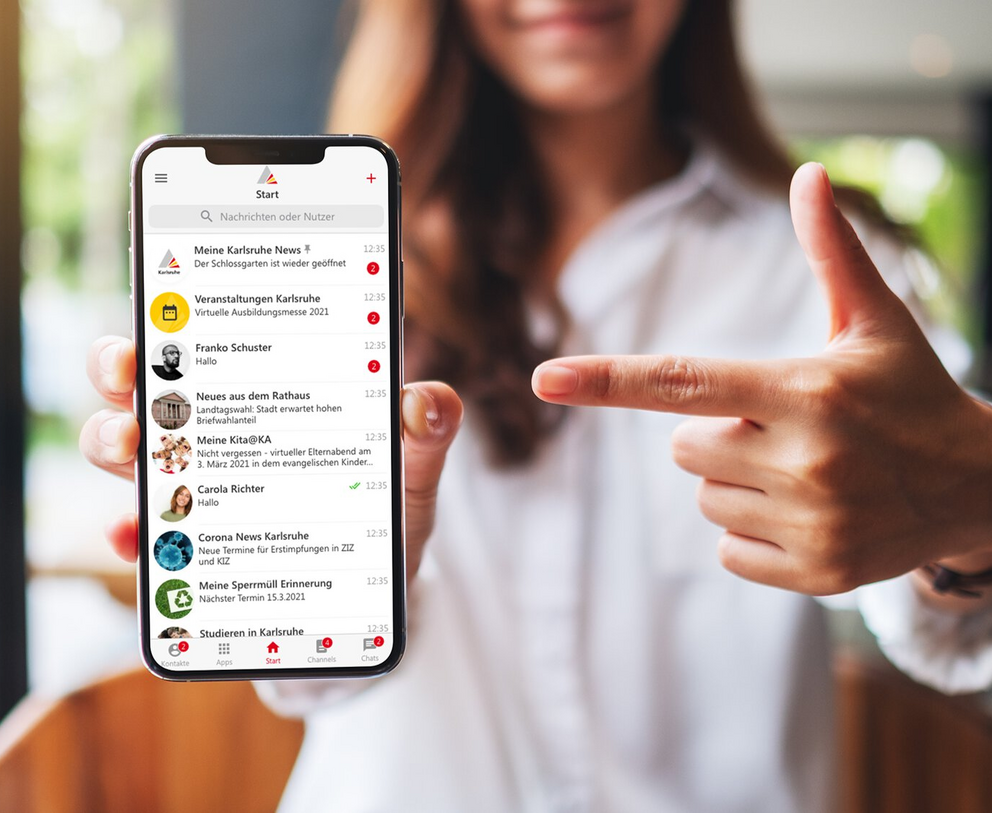 Eine Frau präsentiert ein Smartphone, auf dem die Karlsruhe.App genutzt wird.