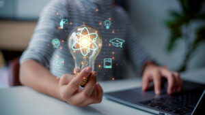 Hand, Arm und Oberkörper eines Schülers, der mit Laptop an einem Tisch sitzt, über der Hand schweben als Overlay Icons für die verschiedenen Schulfächer.