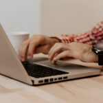 Nahaufnahme männlicher Hände, die auf einer Laptop-Tastatur tippen.