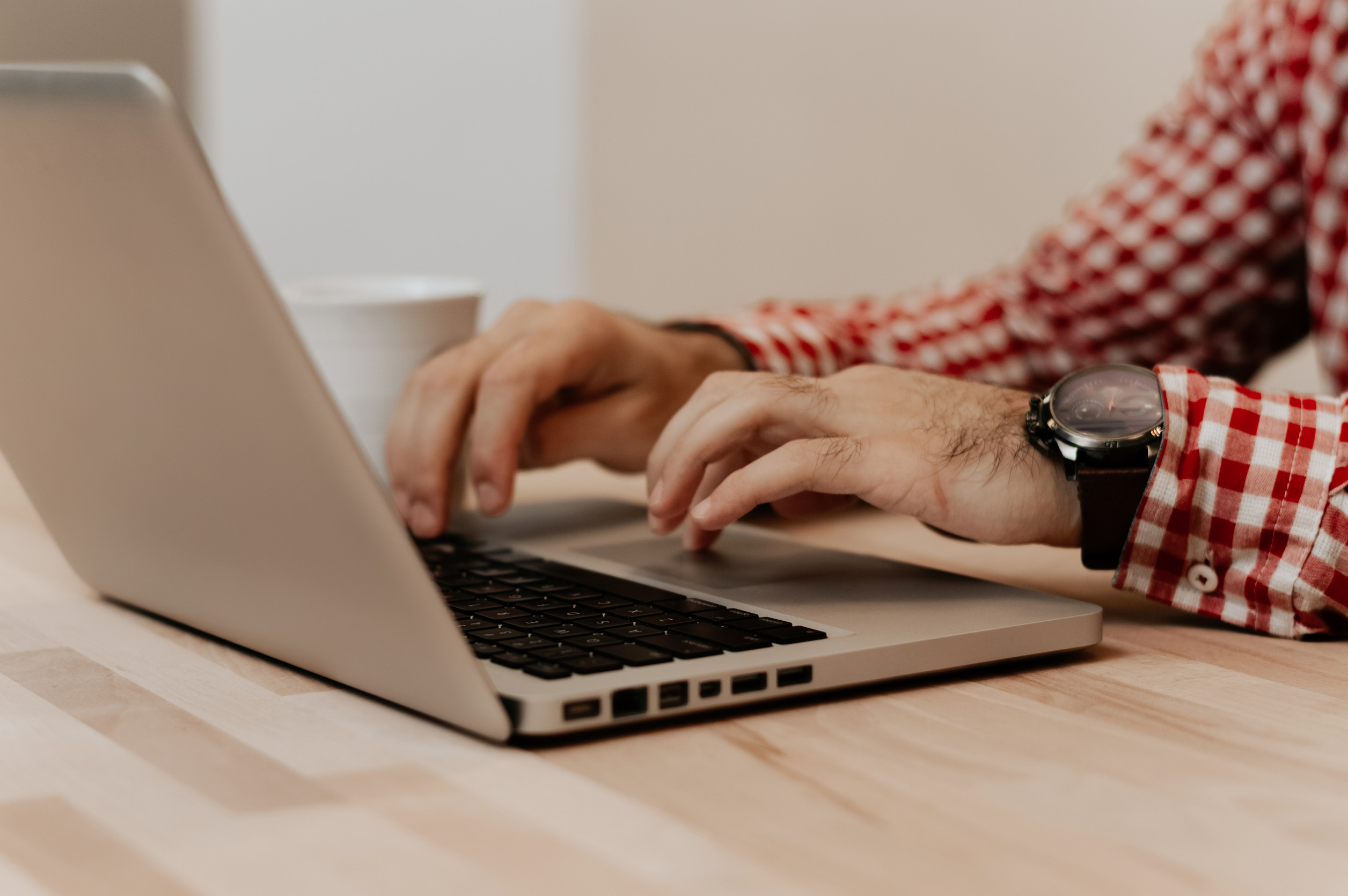 Nahaufnahme männlicher Hände, die auf einer Laptop-Tastatur tippen.