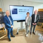 Drei Personen stehen vor einem großen Display und mehreren Präsentationswänden.