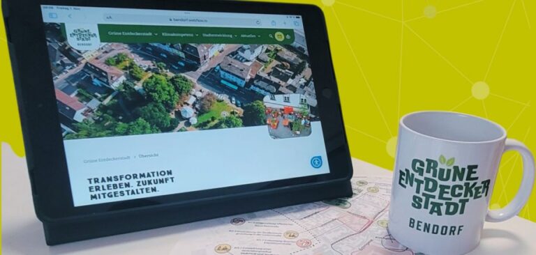 Auf einem Tablet ist die neue Website zur Grünen Entdeckerstadt Bendorf zu sehen, vor dem Tablet steht eine Tasse mit der Aufschrift Grüne Entdeckerstadt Bendorf.
