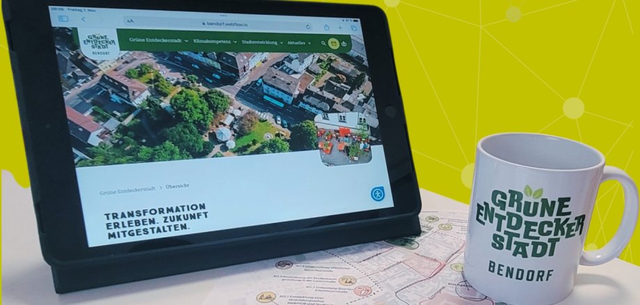 Auf einem Tablet ist die neue Website zur Grünen Entdeckerstadt Bendorf zu sehen, vor dem Tablet steht eine Tasse mit der Aufschrift Grüne Entdeckerstadt Bendorf.