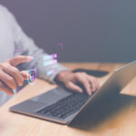 Person am Laptop tippt in die Luft, an der Stelle des Zeigefingers ist ein Log-In-Icon abgebildet.