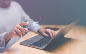 Person am Laptop tippt in die Luft, an der Stelle des Zeigefingers ist ein Log-In-Icon abgebildet.