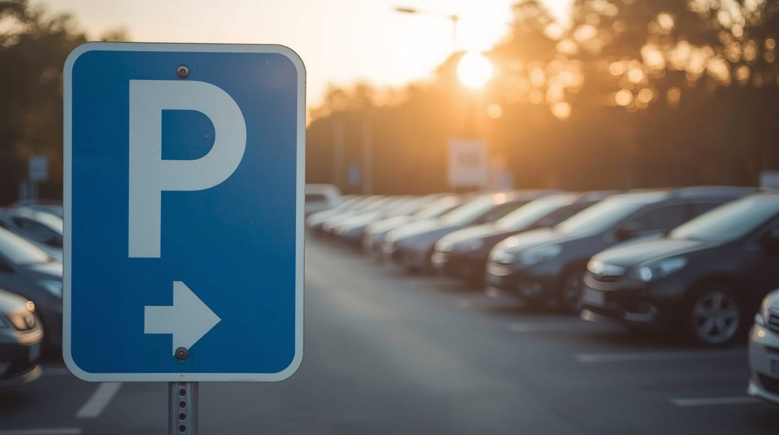 Ein Parkplatzschild steht am Eingang eines Freiluftparkplatzes.