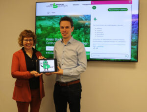 Zwei Personen halten ein Tablet in der Hand, auf dessen Bildschirm Chatbot BOR.KI zu sehen ist.