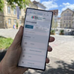 Eine Person hält ein Smartphone in der Hand, auf dessen Bildschirm das Esslinger Serviceportal zu sehen ist.