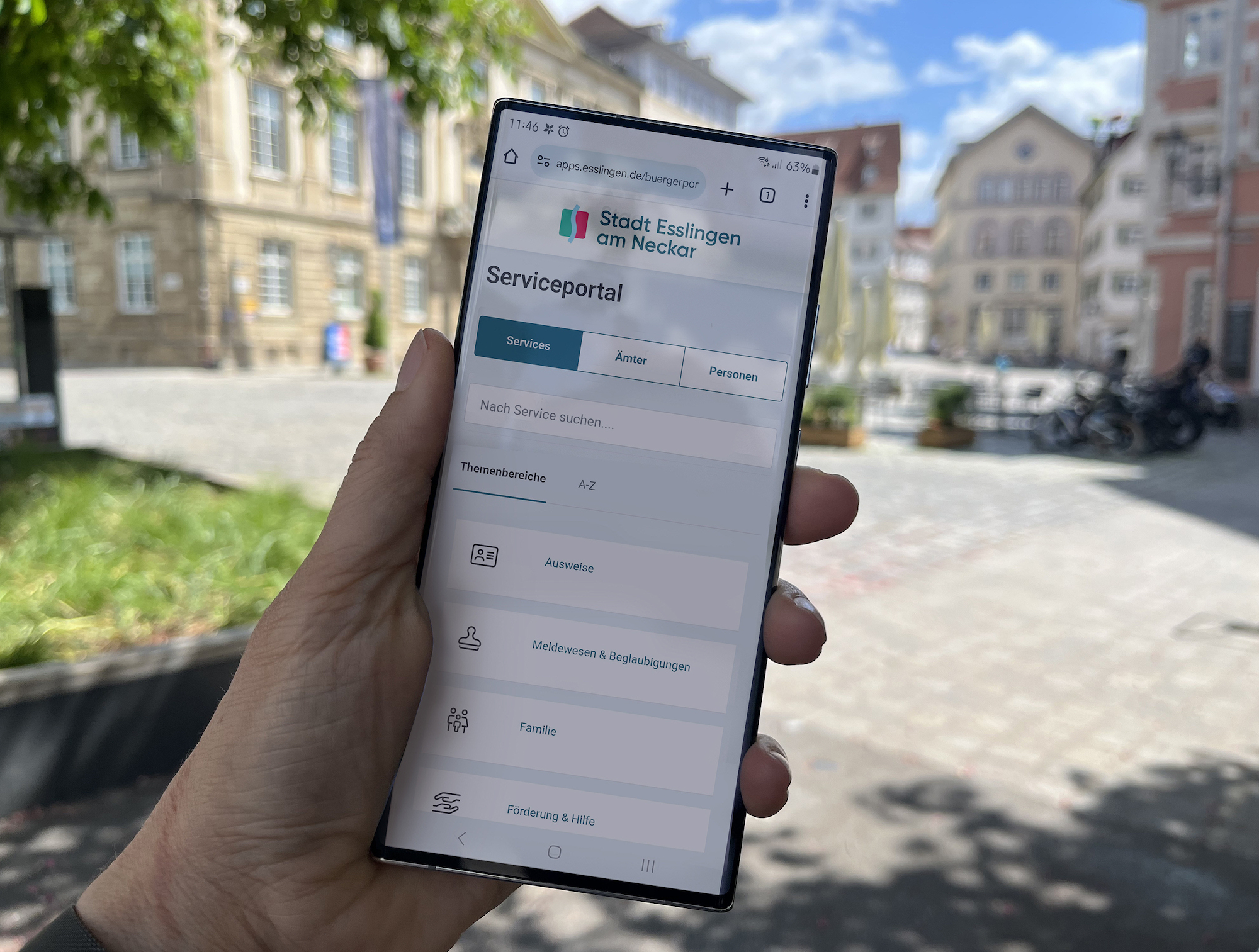 Eine Person hält ein Smartphone in der Hand, auf dessen Bildschirm das Esslinger Serviceportal zu sehen ist.