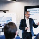 FITKO-Präsident André Göbel beim Vortrag, im Hintergrund ist eine Präsentation eingeblendet.