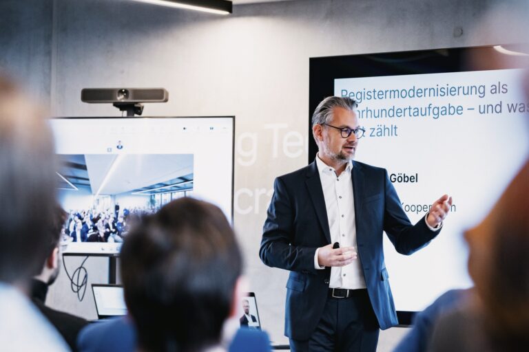 FITKO-Präsident André Göbel beim Vortrag, im Hintergrund ist eine Präsentation eingeblendet.