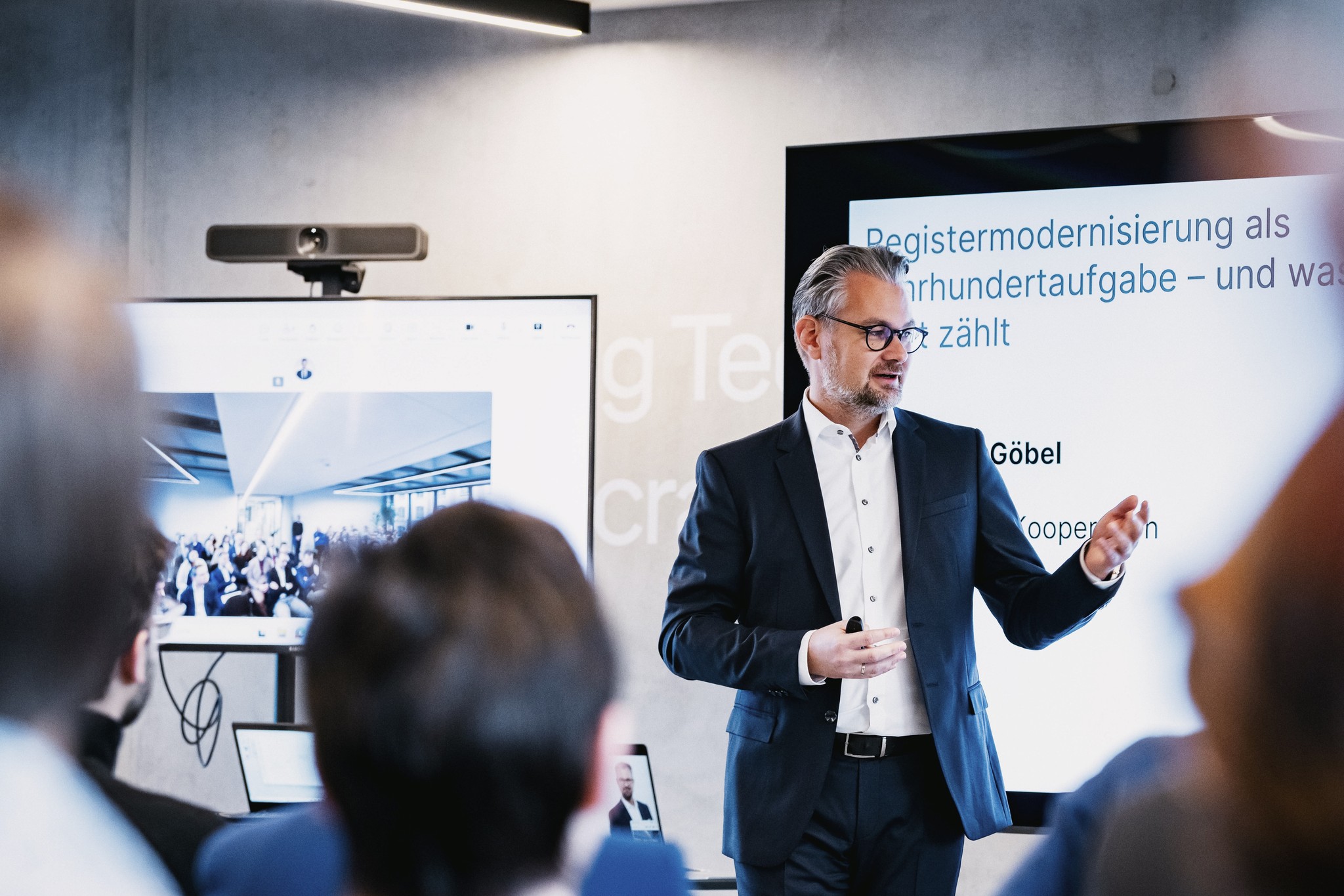 FITKO-Präsident André Göbel beim Vortrag, im Hintergrund ist eine Präsentation eingeblendet.