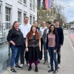 Mehrere Personen stehen zum Gruppenfoto neben einem Gebäude versammelt.