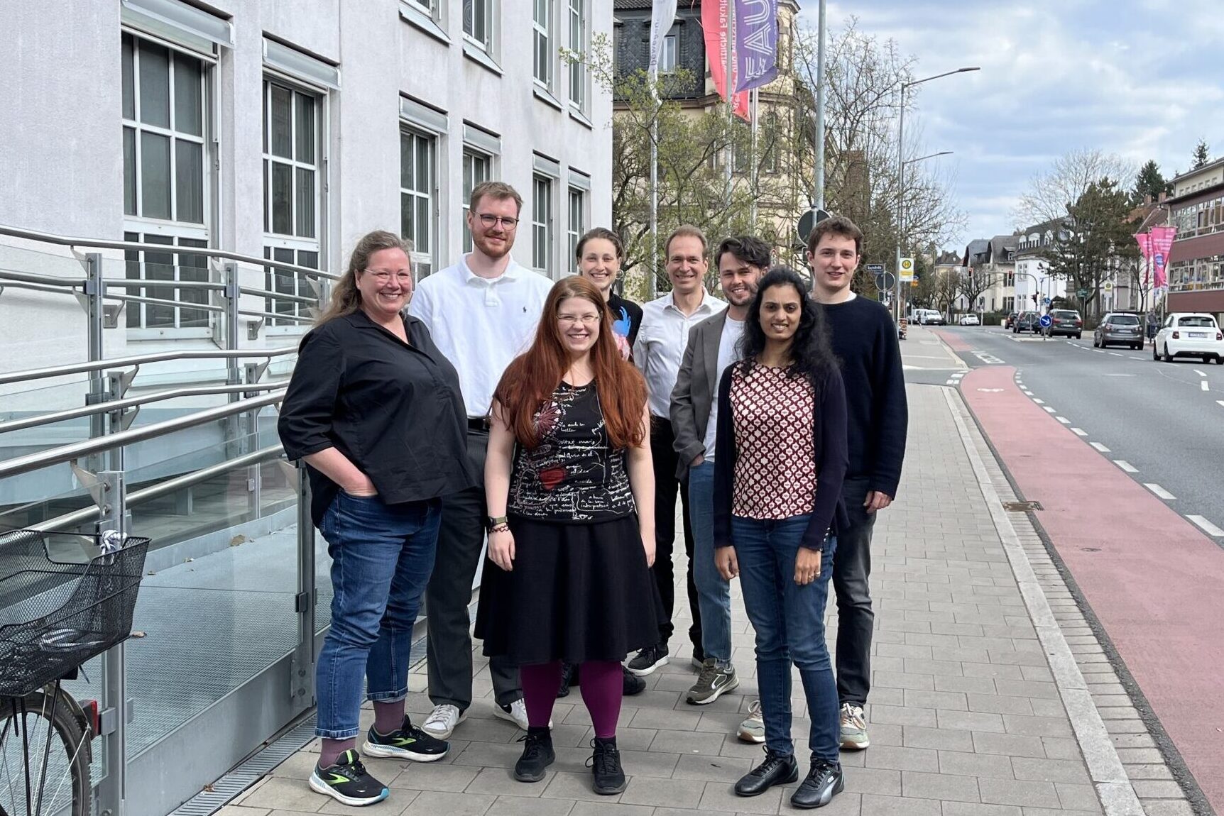 Mehrere Personen stehen zum Gruppenfoto neben einem Gebäude versammelt.