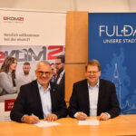 zwei Männer am Tisch sitzen mit papieren vor sich- Kooperation_Fulda_ekom21