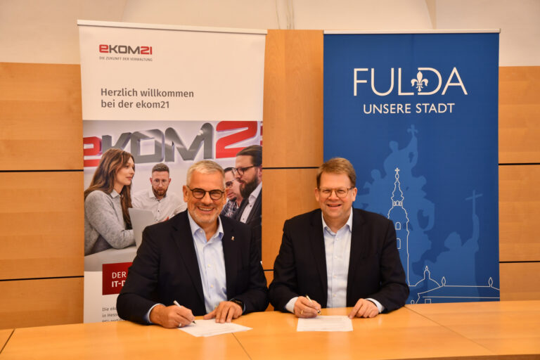 zwei Männer am Tisch sitzen mit papieren vor sich- Kooperation_Fulda_ekom21