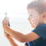 Ein kleiner Junge hält ein Smartphone in der Hand, sein Gesicht ist bedeckt mit biometrischen Linien.
