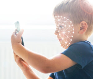 Ein kleiner Junge hält ein Smartphone in der Hand, sein Gesicht ist bedeckt mit biometrischen Linien.