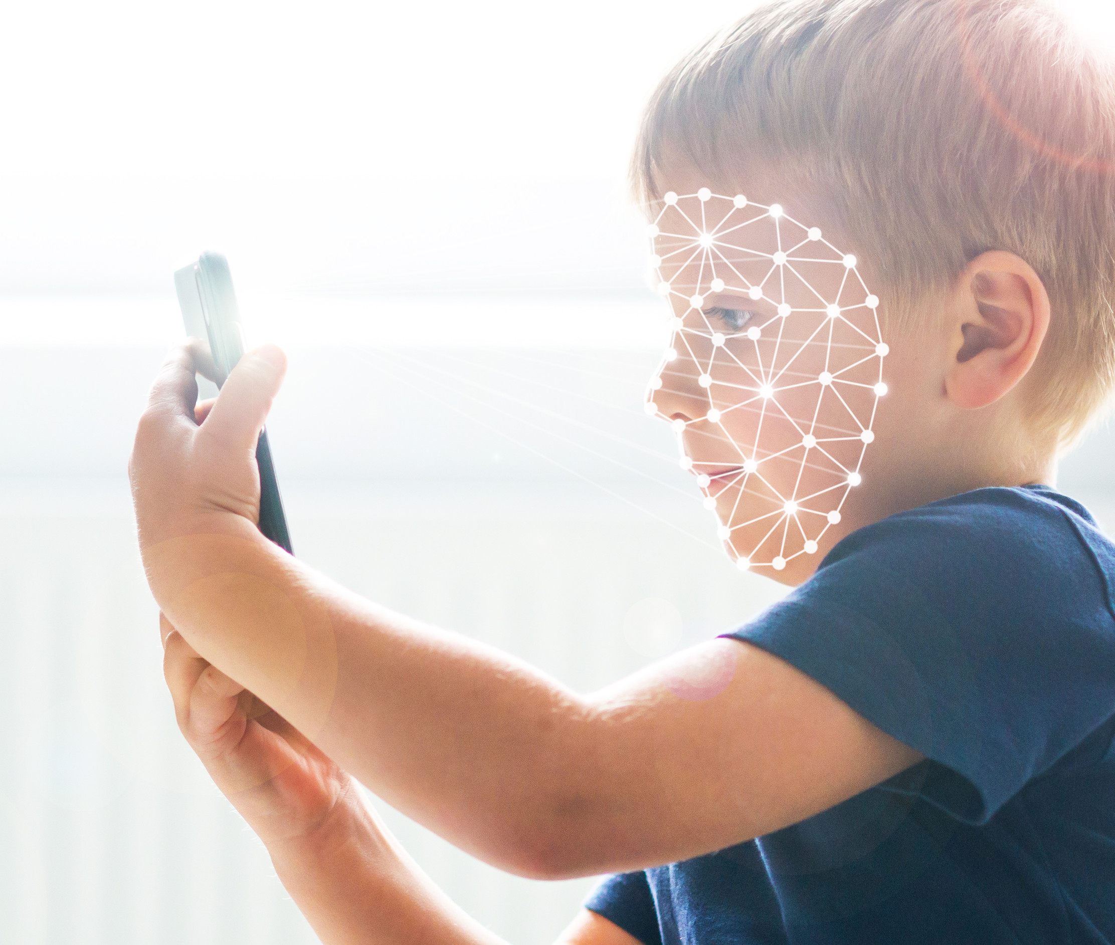 Ein kleiner Junge hält ein Smartphone in der Hand, sein Gesicht ist bedeckt mit biometrischen Linien.