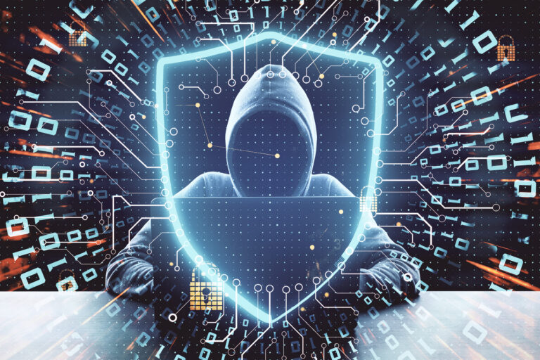 Silhouette einer gesichtslosen Person mit Kapuzenpulli die auf einer Tastatur tippt, im Bildvordergrund ist ein abstrakt dargestelltes Schutzschild zu sehen.