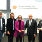 Mehrere Personen stehen nebeneinander, zwei von ihnen bedienen einen Buzzer.