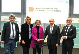 Mehrere Personen stehen nebeneinander, zwei von ihnen bedienen einen Buzzer.