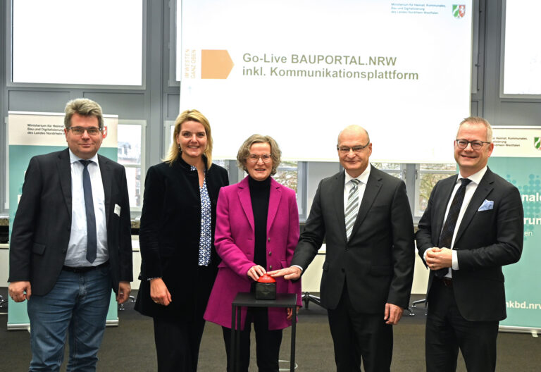 Mehrere Personen stehen nebeneinander, zwei von ihnen bedienen einen Buzzer.