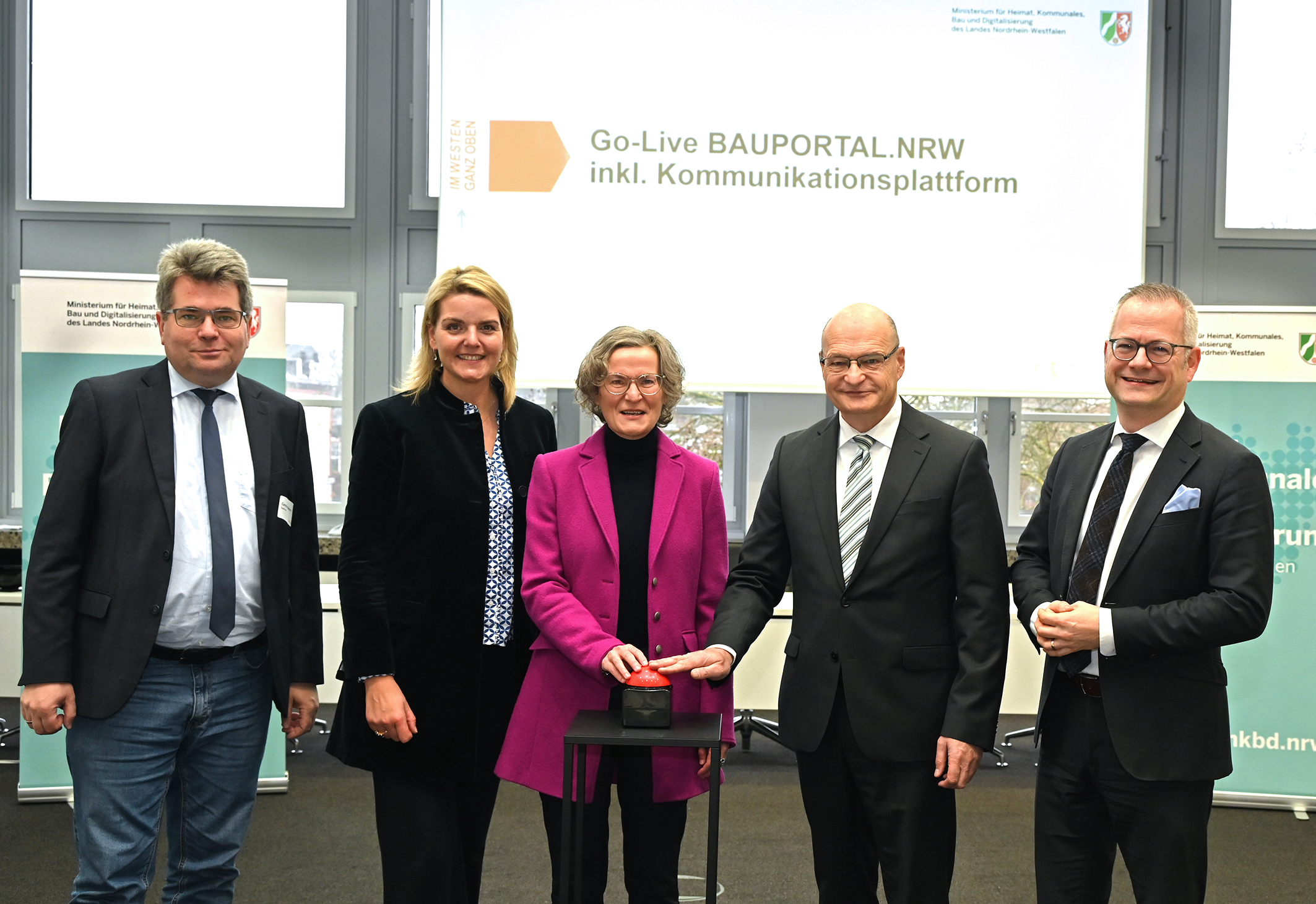 Mehrere Personen stehen nebeneinander, zwei von ihnen bedienen einen Buzzer.