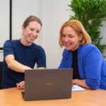 Maren Warnecke zeigt Mira Jago etwas auf dem Bildschirm eines Laptops.