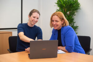 Maren Warnecke zeigt Mira Jago etwas auf dem Bildschirm eines Laptops.