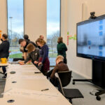 Mehrere jüngere Personen sind in einem Besprechungsraum mit einer Projektarbeit befasst.