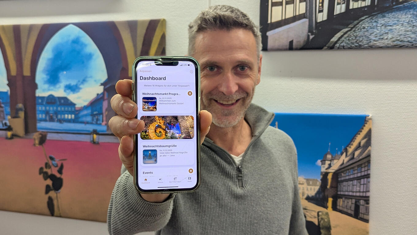 Holger Dettmer präsentiert ein Smartphone, auf dessen Bildschirm die Goslar-App zu sehen ist.